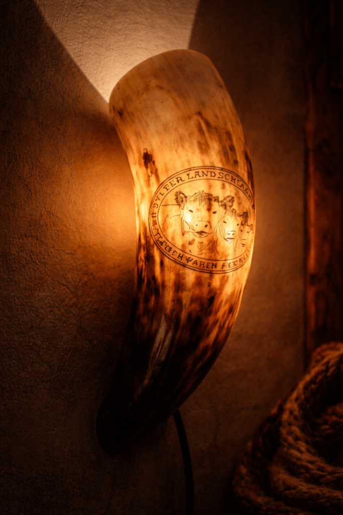 Hornlampe aus Horn mit Gravur eines Tiermotivs, warm beleuchtet
