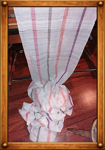 Langer handgewebter Stoff mit farbigen Streifen, vom Webstuhl herunterhängend.